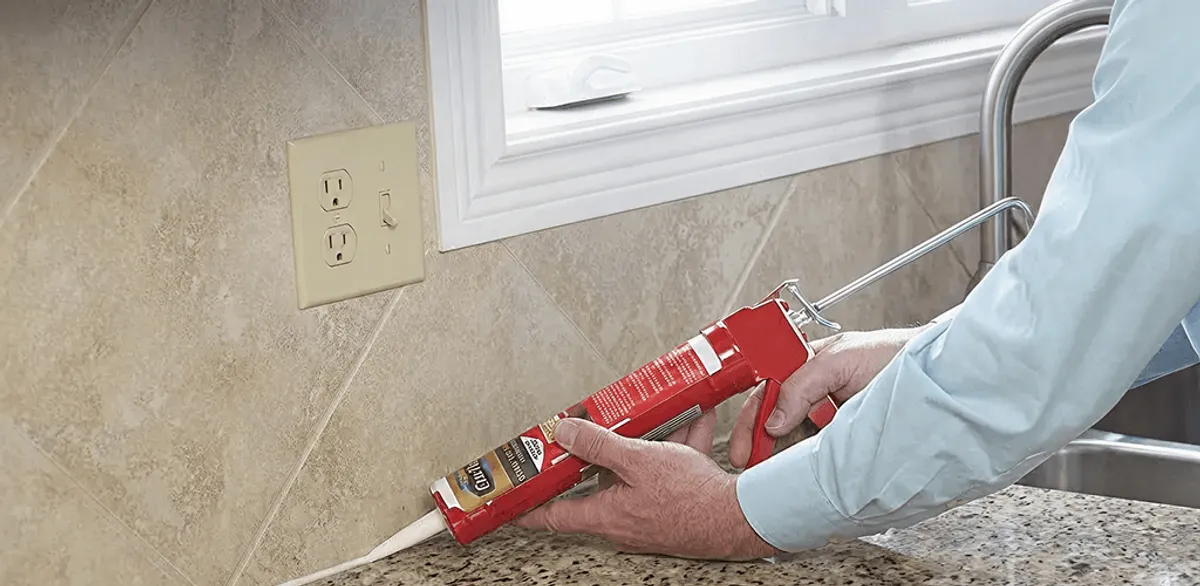 Handyman applying caulk along a kitchen backsplash and countertop seam in Allentown, PA